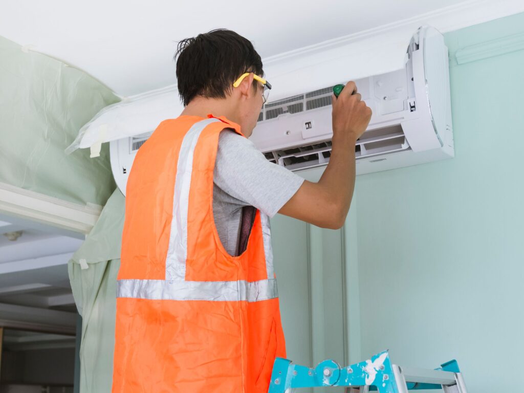 Technician inspecting a wall-mounted air conditioner during service.